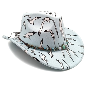Detail of light blue wide brim fedora with white bird prints and ethnic beaded band