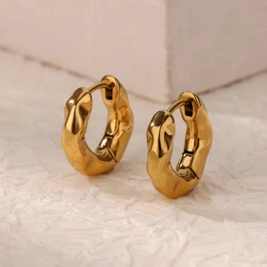 Detailed close-up of gold hoop earrings with irregular lava texture and polished finish