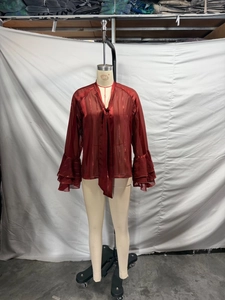 Detail of burgundy sheer chiffon blouse featuring tie-neck and tiered ruffle bell sleeves