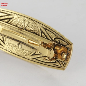 Macro shot of retro gold tree design hair clip showing detailed relief and spring clip