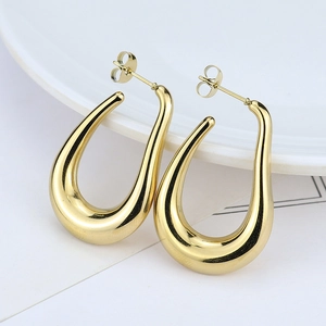 Macro shot of polished gold U-shaped titanium steel hoop earrings with mirror finish