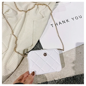 Detail of white PVC jelly bag featuring quilted patterns and gold metal floral clasp