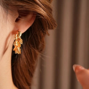 Close-up of a gold-plated leaf hoop earring worn by a model with natural lighting