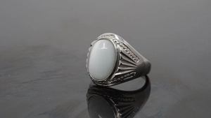 Macro view of stainless steel ring featuring a white cat-eye gemstone and textured details