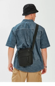 Rear view of a model wearing a medium black waterproof oxford fabric crossbody bag