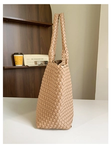 Detail of hand-woven beige tote bag with premium leather texture on a wooden table