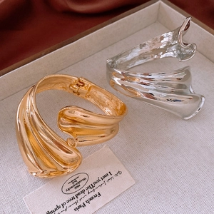 Macro shot of gold and silver irregular pleated wavy bangles on a vintage textured tray