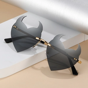 Frameless heart shaped sunglasses with devil horns and grey gradient lenses on a stand