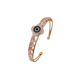 Rose gold open bangle with zircon flower design and blue evil eye charms in a side view