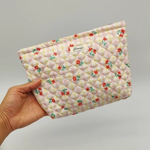 Detail of floral quilted cotton makeup bag with brand label and grid pattern texture