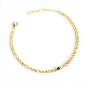Gold plated curb chain bracelet with a green round cut gemstone on white background