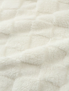 Gros plan détaillé sur le tissu polaire sherpa blanc crème avec un motif de grille doux