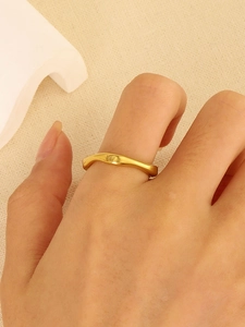 Detail view of minimalist gold wave ring with irregular curved design on model hand