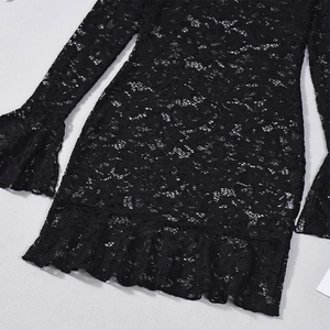 Détail de robe en dentelle noire montrant des manches évasées et un ourlet volanté
