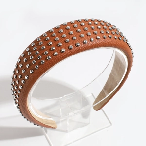 Detail of brown PU leather headband with metallic silver cone studs on a clear stand