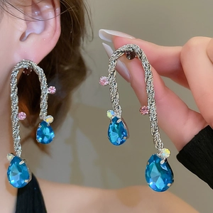 Dettaglio ravvicinato di orecchini a nappa in metallo argento con pietre blu a goccia