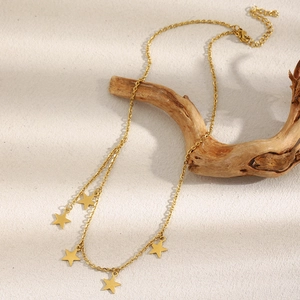 Detail of 18K gold plated stainless steel necklace with star pendants on a wooden branch