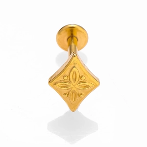 Gros plan sur un piercing labret doré en forme de losange avec motif floral et disque plat