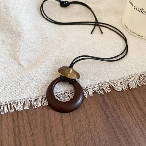 Detail of adjustable black wax rope necklace with brown resin ring and golden metal stud