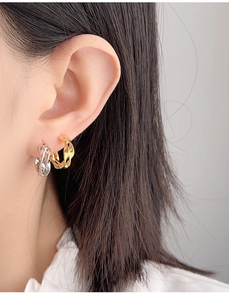 Close-up of twisted Mobius earrings in gold and silver showing on-ear style