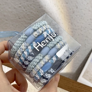 Detail of blue woven hair ties set with oval beads in a clear plastic gift box
