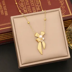 Macro shot of gold bow pendant with white pearls on a vintage jewelry display box