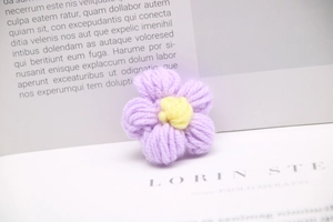 Macro shot of handmade purple crochet flower with yellow stamen for DIY accessories