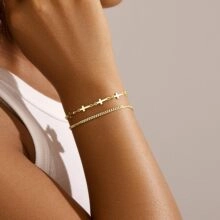 Détail d'un bracelet doré multicouche avec maillons croisés sur le poignet d'une femme