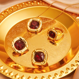 Macro shot of 18K gold plated square red zircon pendant necklace and ring on silk