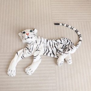 Lifelike white tiger plush toy skin with black stripes and blue eyes on a striped carpet