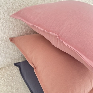 Detail of minimalist solid color pillow covers in pink, red, and blue with hidden zipper