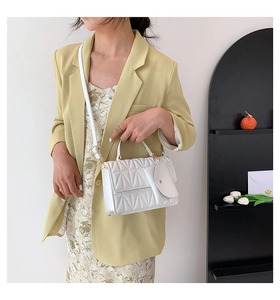 Detail view of white quilted crossbody bag with small round coin purse and gold hardware