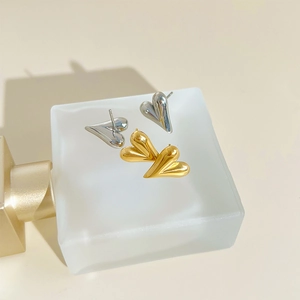 Minimalist 3D heart stud earrings in polished gold and silver finishes on a matte base