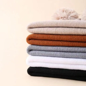 Winter knit beanies with faux fur pom pom in five neutral colors stacked together