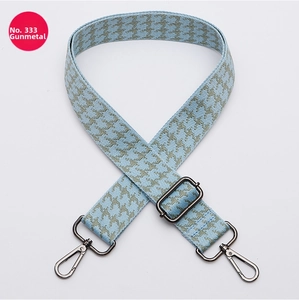 Detail of blue and grey houndstooth bag strap with adjustable gunmetal metal hardware