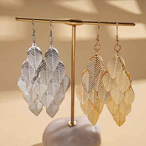 Metallic layered leaf tassel earrings in gold and silver finish hanging on a display stand