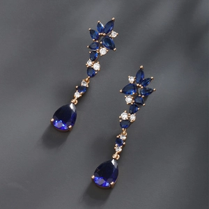 Detail of luxury gold earrings featuring teardrop and marquise cut deep blue gemstones