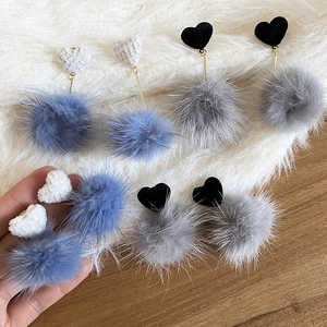 Dettaglio di orecchini a cuore con ciondoli a pompon in peluche blu-bianco e grigio-nero