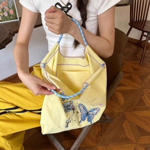 Detail der gelben Oxford-Tasche mit blauer Schmetterlingsstickerei und Seilgriffen