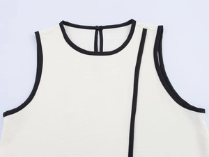 Close-up of white crepe top featuring elegant black contrast trim and a round neckline