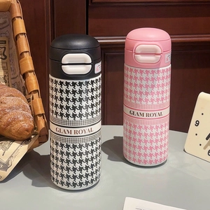 Close-up of houndstooth stainless steel vacuum flasks with GLAM ROYAL logo and pop-up lids