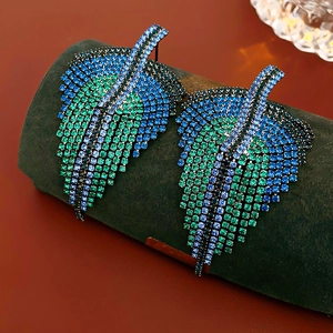 Macro shot of blue and green crystal pavé leaf earrings on a velvet display stand