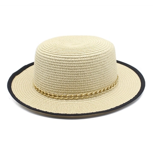 Détail du chapeau canotier avec chaîne dorée et bordure noire contrastée sur la paille