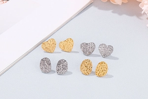 Detail shot of heart and oval gold and silver studs with unique hammered metal texture
