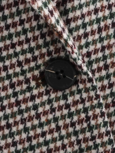 Macro detail of houndstooth plaid blazer featuring large black resin four-hole buttons