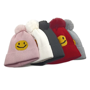 Nahaufnahme der Strickmütze mit Smiley-Stickerei und großem Kunstfell-Bommel in verschiedenen Farben
