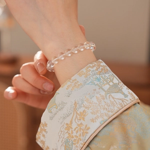 Close-up of clear crystal beaded bracelet on a wrist with silk embroidered cuff