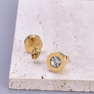 Boucles d'oreilles dorées avec chiffres romains et zircon sur socle en marbre blanc
