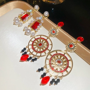 Détail de boucles d'oreilles vintage dorées avec gemmes rouges et perles sur plateau