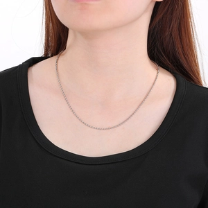 Collier à billes argentées en acier titane porté par un mannequin au design minimaliste